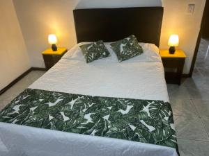 a bed with a green and white comforter and two lamps at CASA CON PISCINA para alojar a toda la familia in Pântano Grande