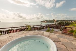 纳塔尔Rede Andrade Comfort的露台上放着一个浴缸，可以俯瞰大海