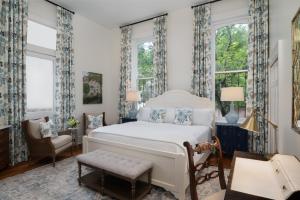 a bedroom with a bed and a chair and windows at Hamilton Turner Inn in Savannah