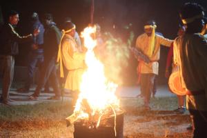 a group of people standing around a fire at Rose wood point in Chālsa Mahābāri