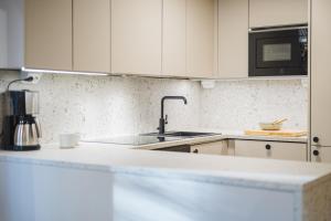 a kitchen with white cabinets and a sink at Luxurious Villa Levin Lepola - Also own private Lapland hut in Kittilä