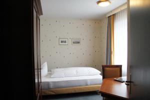 a bedroom with a bed and a desk and a window at Hotel Sonne in Altstätten