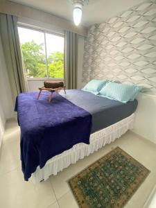 a bedroom with a bed with a purple blanket and a window at Apartamento 2 quartos Rio Centro - Barra Olímpica in Rio de Janeiro