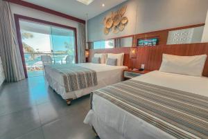 a hotel room with two beds and a balcony at Hotel Paradiso del Sol in Cabo Frio +129 photos