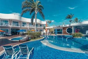 a pool at a hotel with chairs and palm trees at Hotel Paradiso del Sol in Cabo Frio