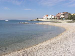 a beach with a rocky shore with buildings in the background at Apartments Sab in Povljana