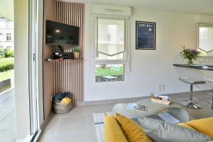 Una sala de estar con un sofá y un televisor. en Escapade - Appartement avec jardin et parking, en Dinan