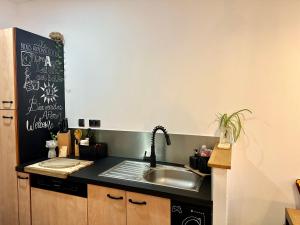 a kitchen with a sink and a black refrigerator at Trésors de la Cathédrale, Maison de Ville sur 4 niveaux in Narbonne