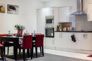 a kitchen with a table and red chairs at Luxury Short Stay Apartment in Hounslow
