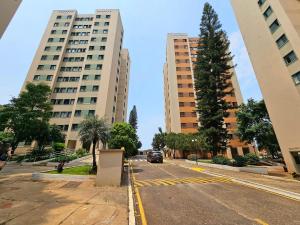 une rue de la ville avec deux grands immeubles et une voiture dans l'établissement Apt 402 com 3 quartos 10min Paraguai e 5min centro, à Foz do Iguaçu