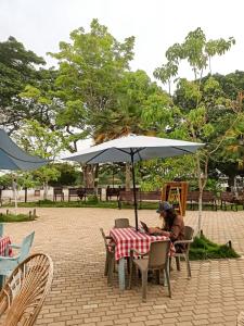a woman sitting at a table under an umbrella at Hostel Pueblito Magico Mompós in Santa Cruz de Mompox