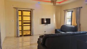 a living room with a black leather couch and a door at Odoux in Adékplovi