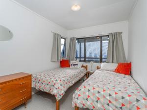a bedroom with two beds and a dresser and a window at Whanga Bach - Whangamata Holiday Home in Whangamata