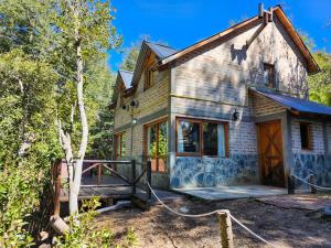 a stone house with a driveway and a porch at Aparts y Cabañas Costa de Lago in Villa Pehuenia