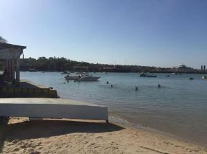 una panchina su una spiaggia con barche in acqua di Loft na praia com vista a Itaparica