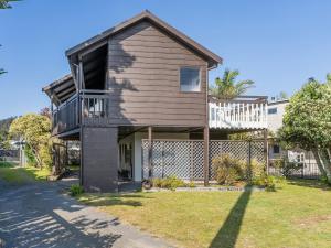 a house with a balcony and a yard at Whanga Bach - Whangamata Holiday Home in Whangamata