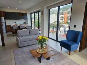 a living room with a couch and a vase of flowers at Cómodo Apartamento zona Romántica con alberca 503 in Puerto Vallarta