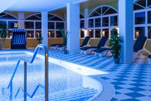 a swimming pool in a hotel with chairs and tables at Ferienpark Markgrafenheide in Markgrafenheide