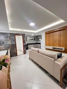 un salon avec un canapé et une cuisine dans l'établissement Apartamento com 3 quartos no centro de Domingos Martins, à Domingos Martins