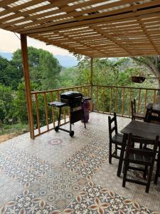 porche cubierto con mesa, sillas y parrilla en Villa San Martín, en Sopetrán