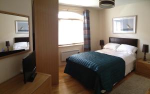1 dormitorio con cama, espejo y TV en Seaview Reenellen en Valentia Island