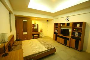 ein Wohnzimmer mit einem Bett und einem TV in der Unterkunft At Home Phetkasem in Bangkok