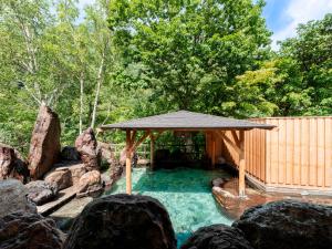 a swimming pool with a gazebo in a garden at Sounkaku in Kamikawa