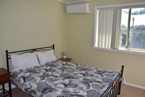 un dormitorio con una cama y una ventana en Village Centre 3 - Bring your own linen., en South West Rocks