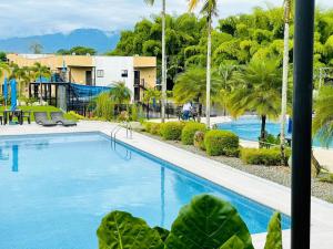 a pool at a resort with palm trees at Vacaciones Eje Cafetero Parque del Cafe WIFI 114C in La Tebaida