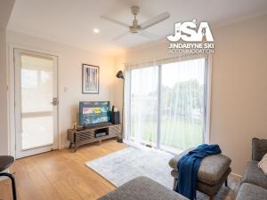 a living room with a tv and a large window at Homeski in Jindabyne