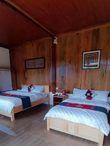 two beds in a room with wooden walls at Mù Cang Chải Dream House in Mù Cang Chải