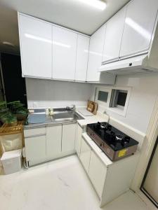 a white kitchen with a stove and a sink at Clean & All new - Songridan-gil, Seokchon Lake, Lotte World, KSPO Dome, Olympic Park, Han River, Asan Hospital, Coex in Seoul +17 photos