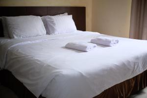 1 cama blanca grande con 2 toallas plegables. en De Nusantara Hotel Syariah, en Medan