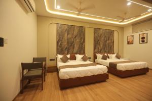 a hotel room with two beds and a chair at Hotel Raghavji in Rādhanpur
