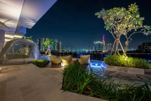 a rooftop patio with a view of the city at night at Saigon Metropole - Residences Complex - Free Pool, Sauna Room, Gym, Yoga Room, Golf Room in Ho Chi Minh City