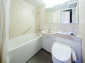 a white toilet sitting next to a sink in a bathroom at Daiwa Roynet Hotel Wakayama in Wakayama