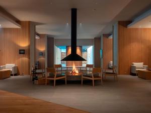 a lobby with a fireplace with chairs and a table at Sounkaku in Kamikawa