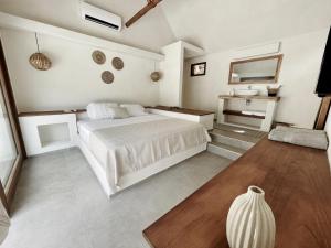 une chambre blanche avec un lit et une salle de bain dans l'établissement Mahalo Boutique B&B, à Popoyo
