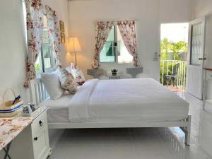 a white bedroom with a large bed and windows at โฟร์วิลล่า เขาใหญ่ in Pak Chong +5 photos