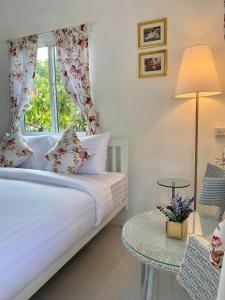 a bedroom with a bed with a window and a table at โฟร์วิลล่า เขาใหญ่ in Pak Chong