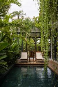 una piscina con 2 sillas y una mesa en un jardín en Nongnia Beach Villa, en Tân Thành (1)