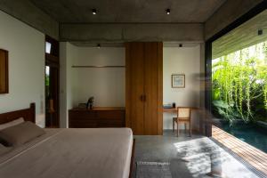 Un dormitorio con una cama y un escritorio y una ventana. en Nongnia Beach Villa, en Tân Thành (1)