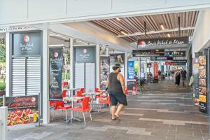 a man walking through a shopping mall with tables and chairs at Stylish CBD retreat - 8 Il Palazzo in Cairns