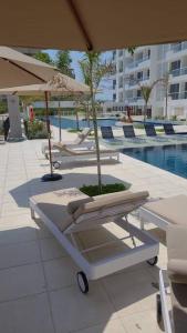 a group of lounge chairs and an umbrella next to a pool at Apartamento con diseño exclusivo, vista al mar in Santa Marta +15 photos