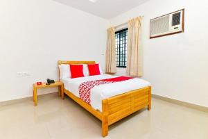 a bedroom with a bed with red pillows and a window at Hotel Tri-Star Residency in Cochin