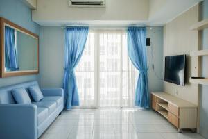 a living room with a blue couch and a large window at Spacious and Nice 2BR at Casa De Parco Apartment By Travelio in Tangerang