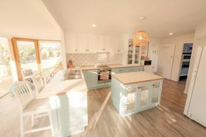 a kitchen with white cabinets and a table and chairs at Shellwater at Sellicks Beach Large Double Block Coastal Family Getaway in Sellicks Beach