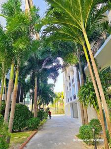 a person walking down a street next to palm trees at AD resort ชะอำ in Ban Bo Khaem