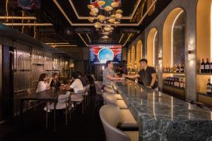 un gruppo di persone sedute al bancone di un ristorante di Cube Social Boutique Capsule Hotel at Boat Quay a Singapore