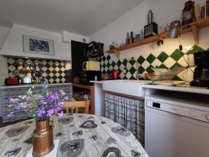 a kitchen with a table with a vase of flowers on it at Maison de campagne paisible avec terrasse et animaux admis - FR-1-582-505 in Sembadel +27 photos